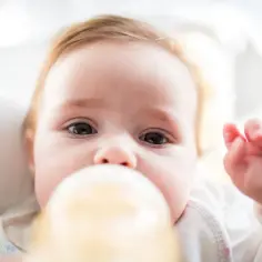 Urocze niemowlę pije mleko z butelki. Ważne jest, jaka temperatura mleka dla noworodka jest odpowiednia, by zapewnić mu komfort i bezpieczeństwo.