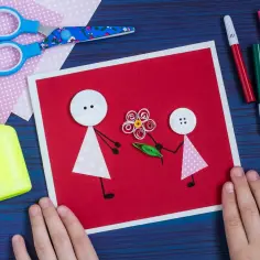 Ręcznie robiona kartka na Dzień Mamy: dziecko tworzy postać z guzika i papieru, która wręcza kwiat. Świetny pomysł, co można zrobić na Dzień Mamy!
