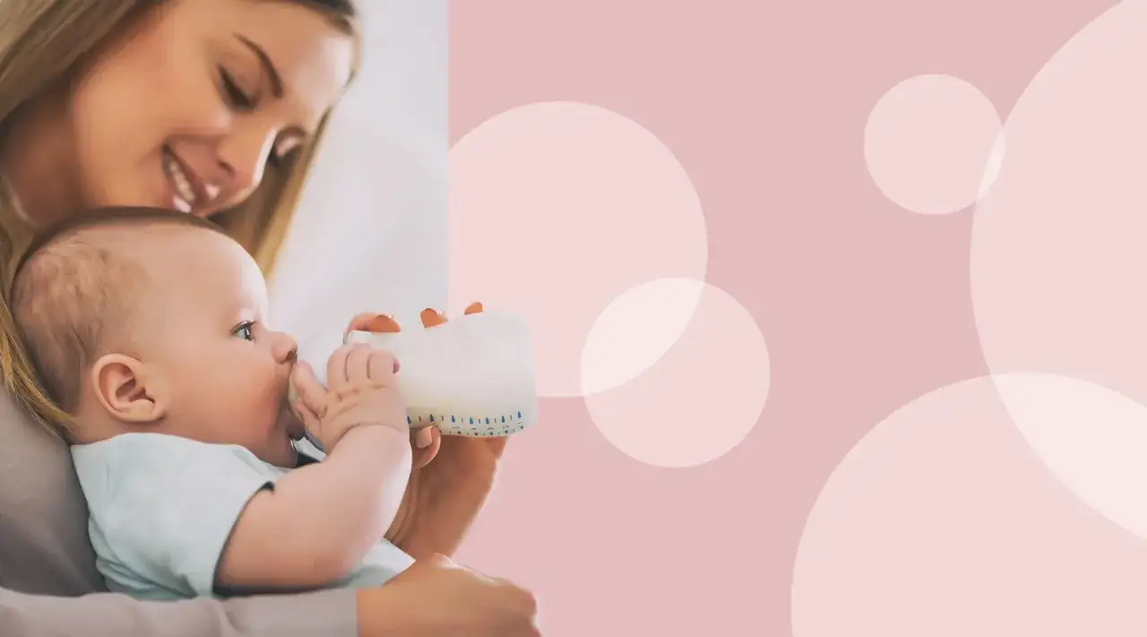 Uśmiechnięta mama karmi butelką niemowlę. Kluczowe jest, jaka temperatura mleka dla noworodka, by zapewnić mu komfort.